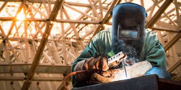 MMA-svetsning, industrisvetsare som svetsar tillverkade konstruktioner i fabrik, svetsprocess genom sköldmetallbågsvetsning (SMAW) eller elektrodsvetsning.