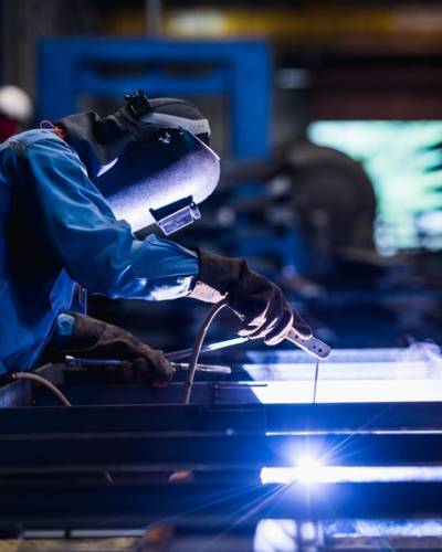 MMA-svetsning, industrisvetsare som svetsar tillverkade konstruktioner i fabrik, svetsprocess genom sköldmetallbågsvetsning (SMAW) eller elektrodsvetsning.